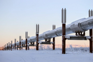 An outdoor oil pipeline runs along a snow-laden field